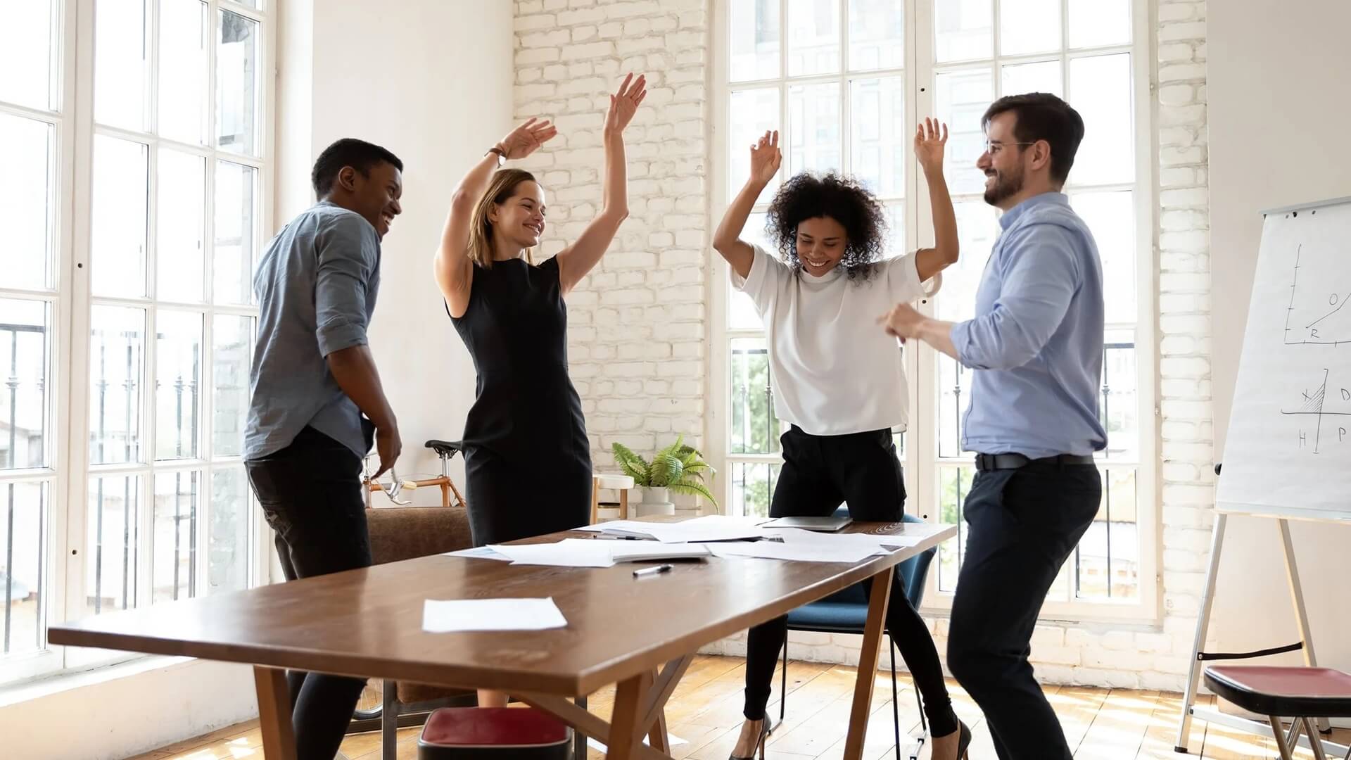 Professionals in business attire laughing and dancing together, illustrating that Authenticity in Leadership is not a fixed trait but a dynamic, responsive 