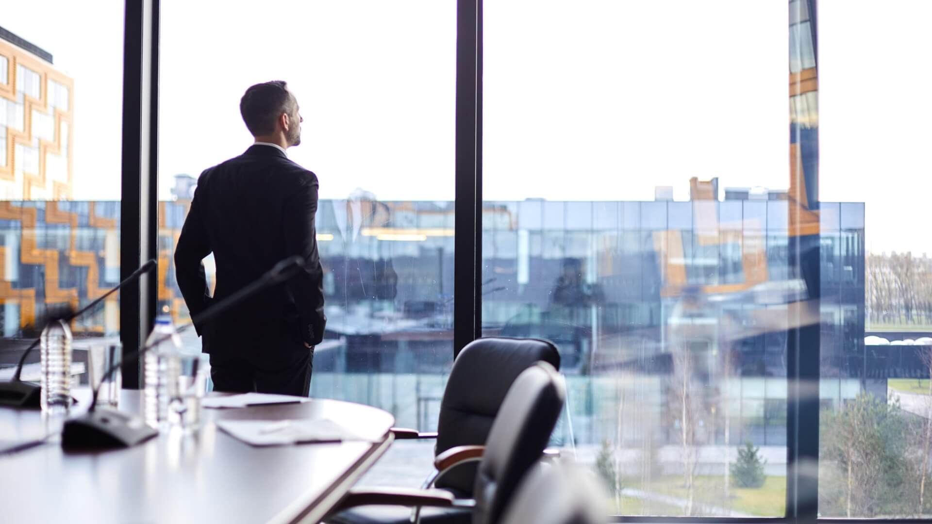 man looking out the window to reflect on organisational systems and leadership